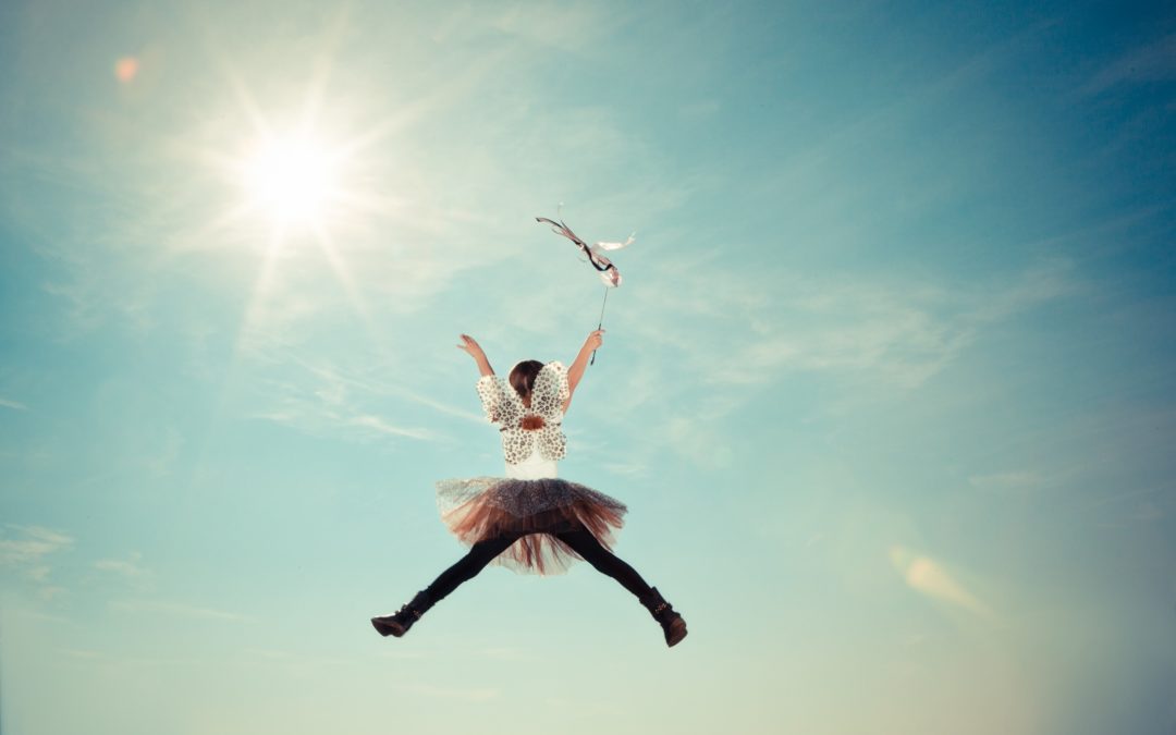 A young girl wearing butterfly wings jumps in the air